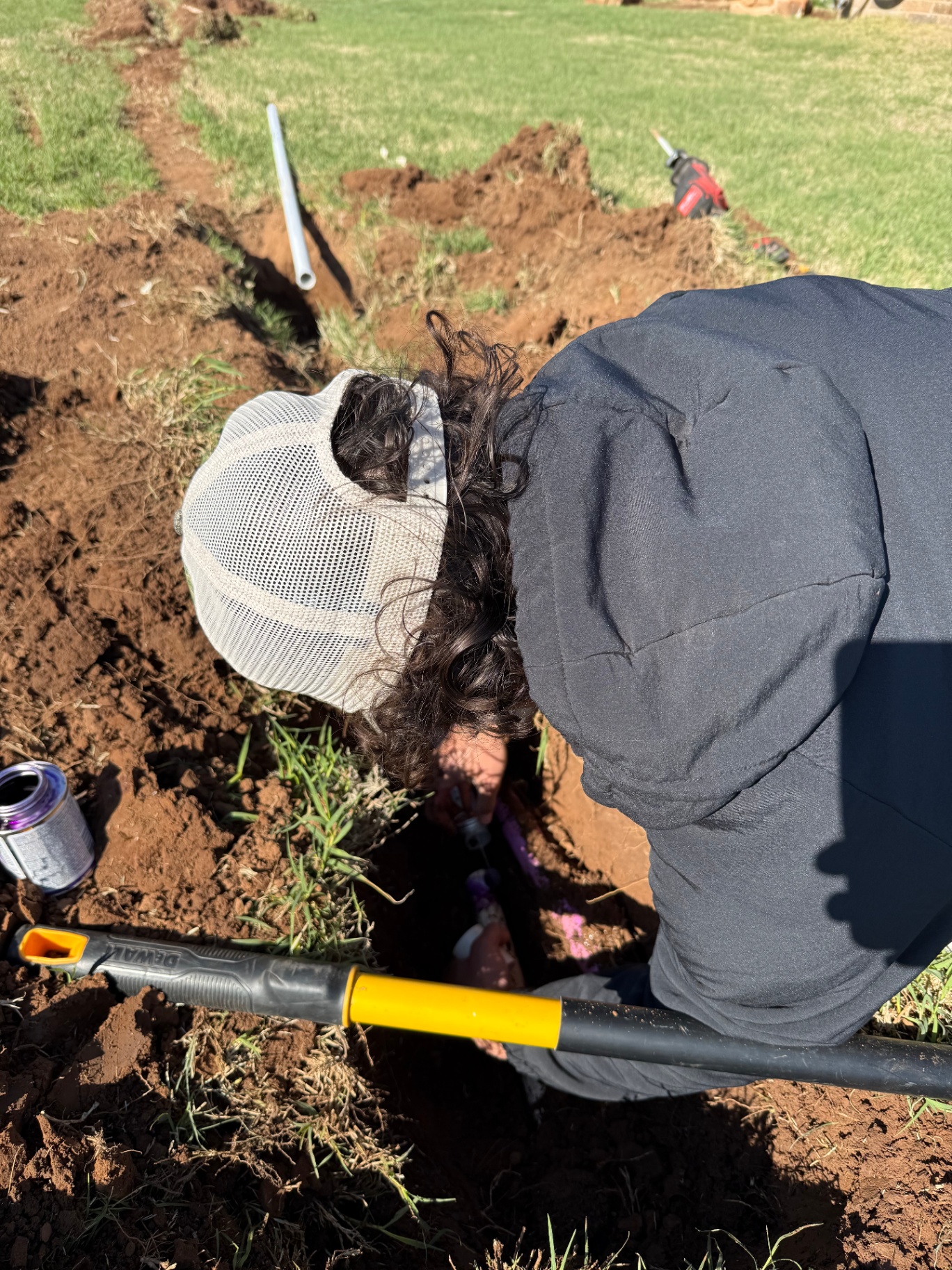 crew member gluing PVC sprinkler pipe in a freshly dug trench in Tuttle Oklahoma