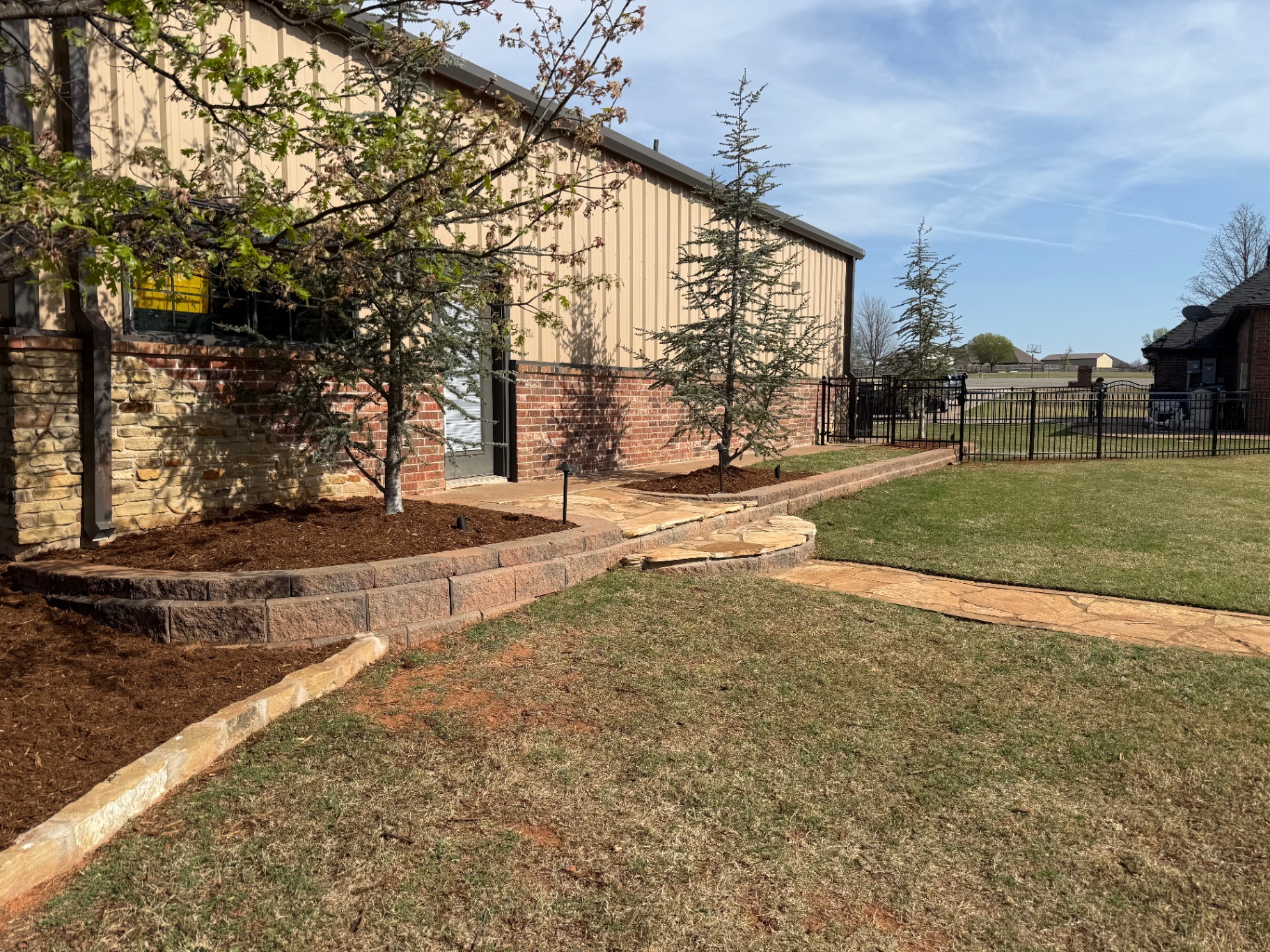 flagstone walkway with stacked retaining wall and mulched beds in Tuttle Oklahoma