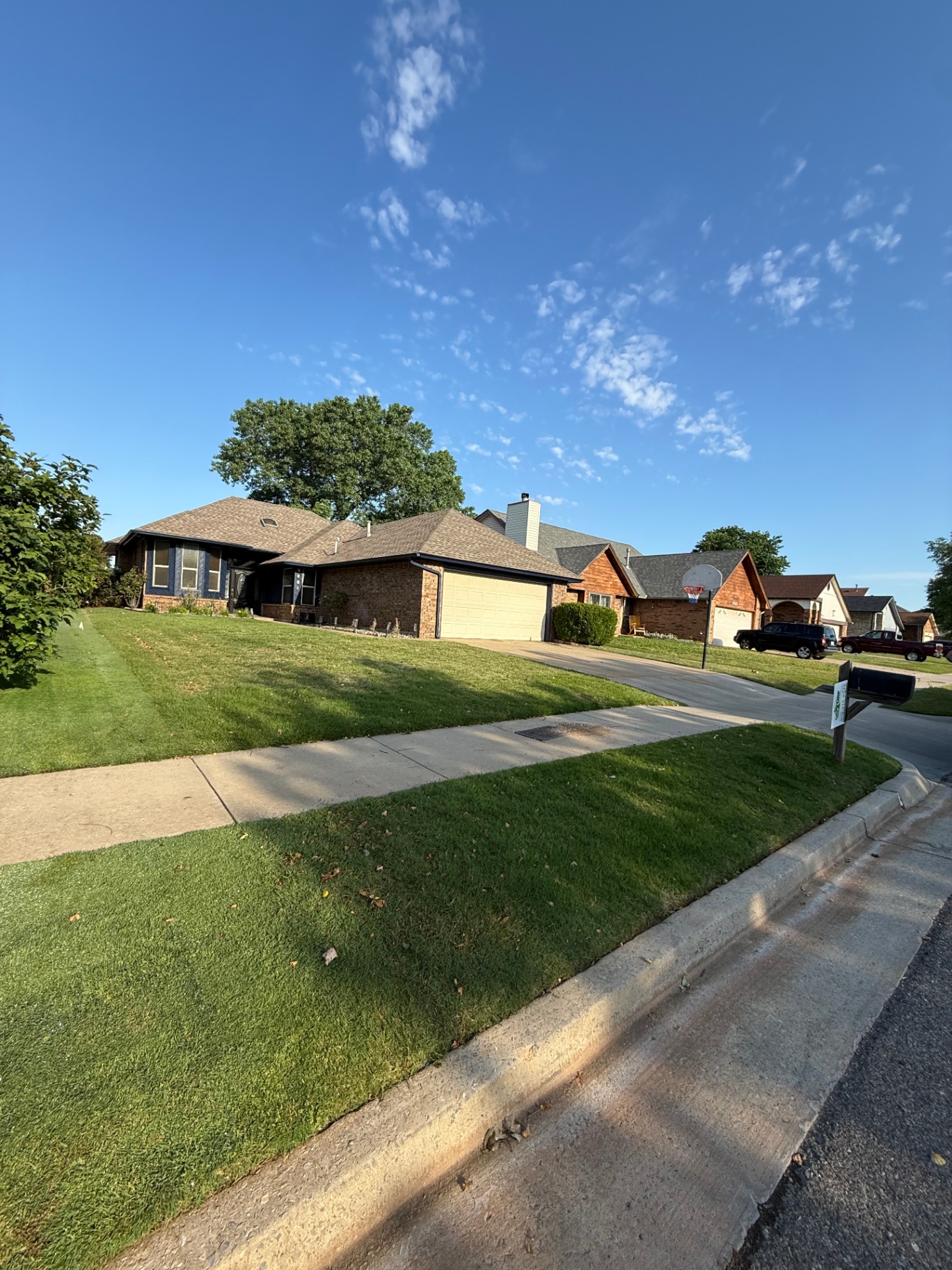 front yard and driveway view of a brick home after lawn service in Oklahoma City